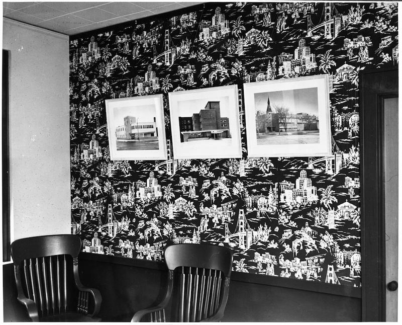 Office interior of George J. Grant Construction Company. A pair of office chairs set against a wall with three framed photos of buildings.